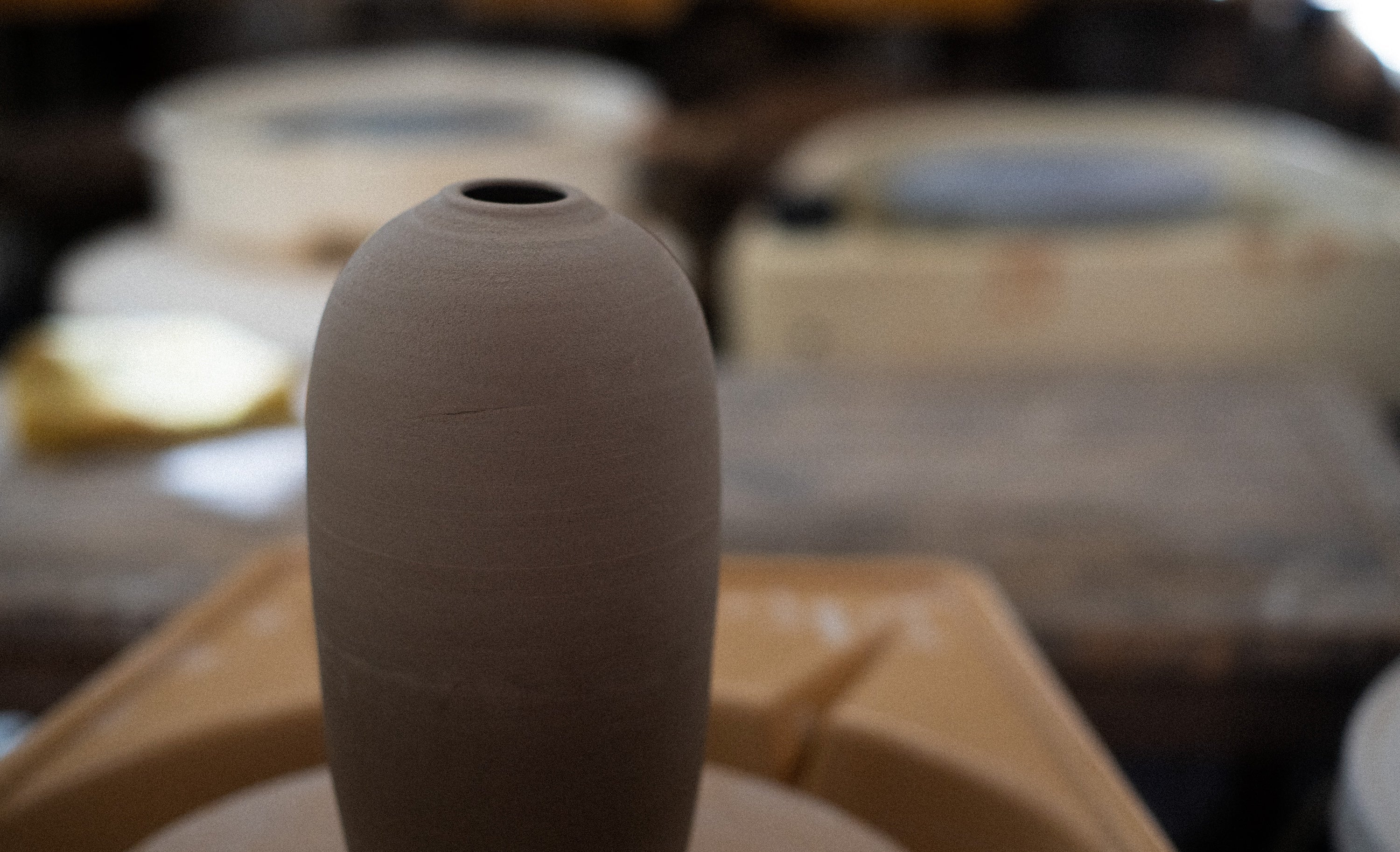 Clay vase on a pottery wheel with blurred background
